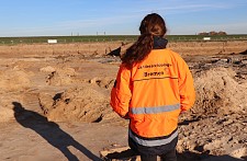 eine Frau mit einer orangen Sicherheitsjacke. Aufschrift: Landesarchäologie Bremen