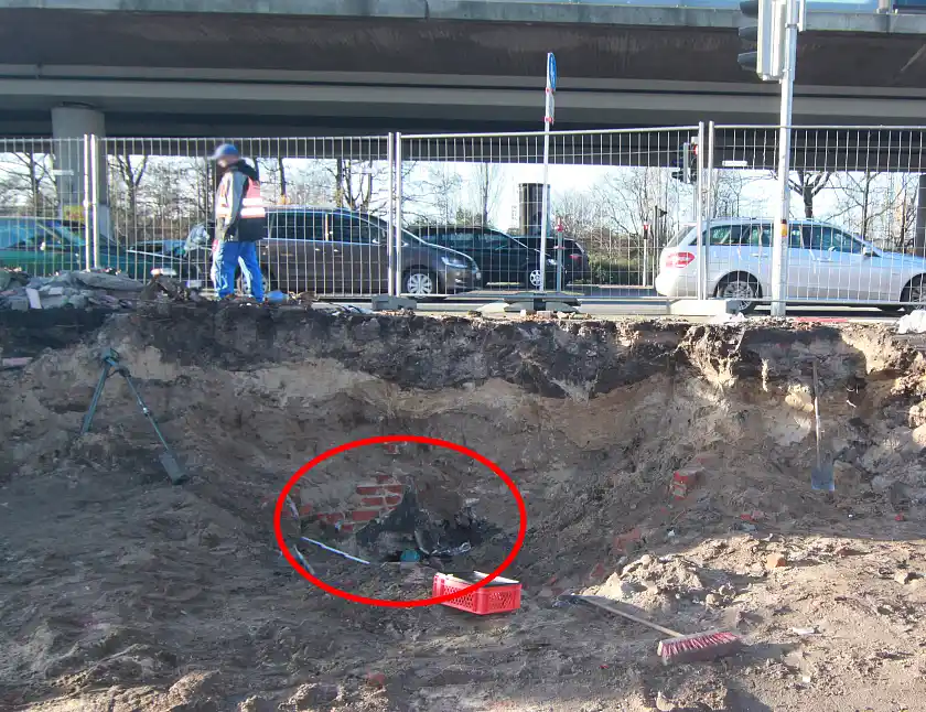 Ausgrabungsfläche, kurz unter dem Straßenpflaster, im Hintergrund befindet sich eine stark begfahrene Straße