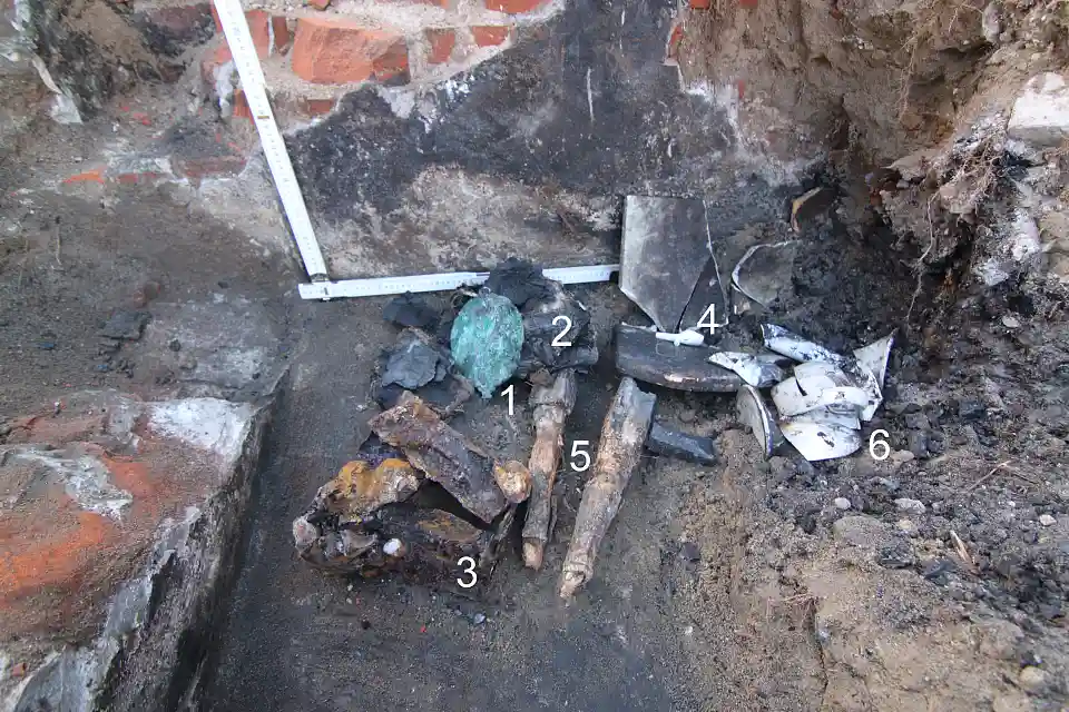 stark vergangene Funde: Plakette von A. Bebel, verbranntes Buch, Geldkassette, Tonpfeife, Tischbeine mit Tischplatte, Nachttopf