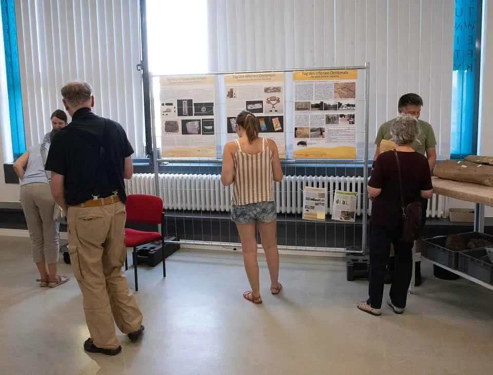 Besuchende schauen Poster an. Rechts im Bild zusehen: Walknochen